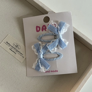 Dettaglio di fermagli per capelli a fiocco blu con pizzo bianco e qualità artigianale