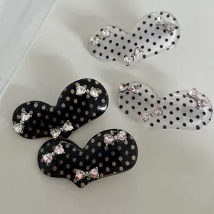 Detailed view of heart-shaped polka dot hair clips with sparkly rhinestone bow decorations