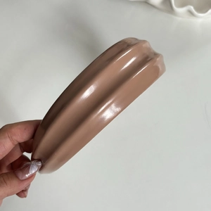 Gros plan sur un bandeau large plissé en cuir PU marron clair au fini brillant texturé