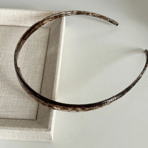 Close-up of minimalist tortoiseshell headband with anti-slip teeth on linen tray