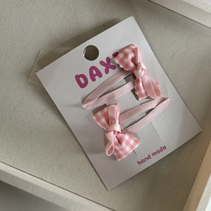 Detail van roze en wit geblokte strik haarspelden met geschulpte randen op een kaart