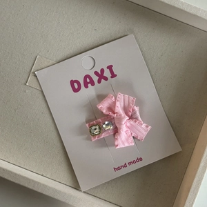 Detail van roze satijnen strik haarclip met vierkante en ronde strass-steentjes op kaart
