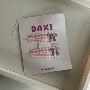 Detail van de roze geblokte stoffen haarspelden met zilveren metalen strikjes