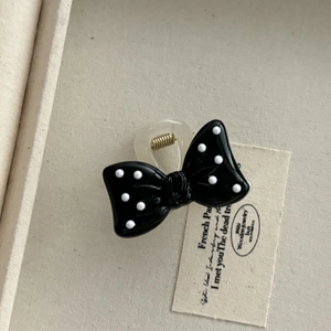 Detail of retro polka dot bow hair claw clip with golden metal spring and smooth finish
