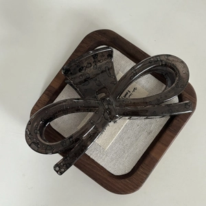Brown marble pattern acetate hair claw clip with bow design in a wooden tray