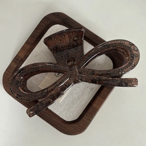 Brown acetate butterfly bow claw clip with tortoiseshell texture on vintage linen background