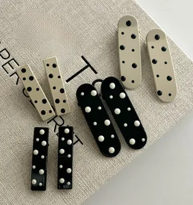 Close-up of minimalist polka dot hair clips in oval and rectangular acetate shapes