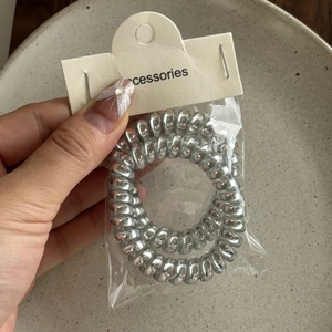 Set of two silver metallic spiral hair coils in minimalist transparent packaging