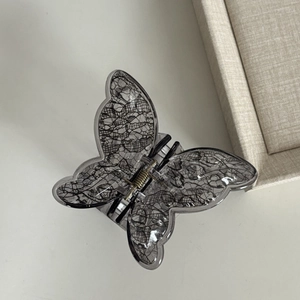 Close-up of butterfly hair claw with grey transparent acrylic and black lace texture