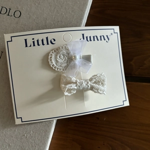 Dettaglio di fermagli per capelli in pizzo bianco con fiocchi in chiffon e perle su carta