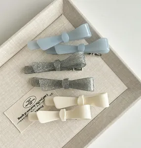 Detailed macro view of mint blue and cream acetate bow hair clips on a soft display tray