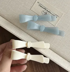 Detail showing mint blue and cream acetate bow hair clips on a soft textured fabric