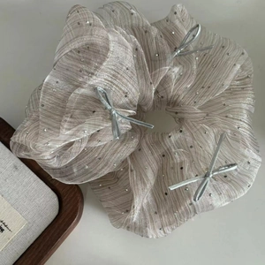 Macro detail of organza scrunchie with sparkling rhinestones and silver bow decorations