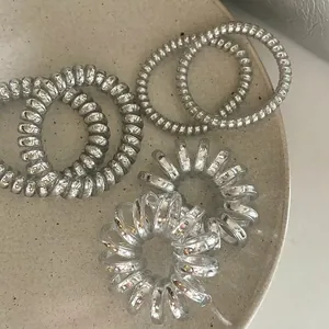 Set of 6 minimalist silver and transparent spiral telephone wire hair coils in a tray