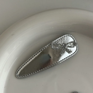 Silver metallic leather BB clip with sparkling rhinestone bow and textured stitching details