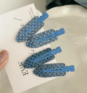 Close-up of four blue denim polka dot duckbill hair clips on white card holder
