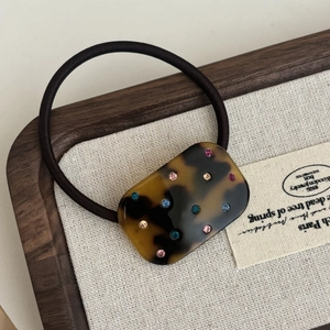 Macro detail of tortoiseshell acetate hair tie with colorful sparkling rhinestones