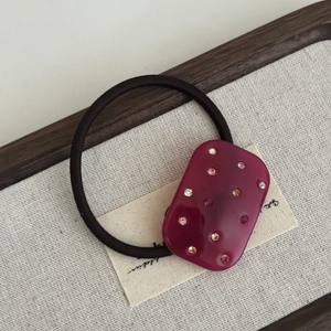 Close-up of elegant burgundy acetate hair tie with colorful crystal rhinestones inlay