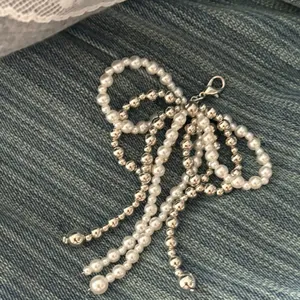 Beaded bow tassel shoe charm with faux pearls and silver metal beads on denim background