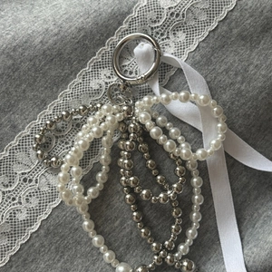 Macro detail of layered pearl bead chain accessory with silver ring and ribbon decoration