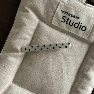 Detailansicht einer französischen Haarspange mit schwarzen Punkten auf beigem Canvas-Stoff