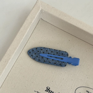 Detail of blue polka dot denim hair clip with seamless matte metal duckbill grip