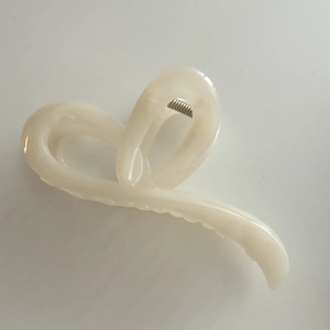 Détail de la pince à cheveux en résine crème avec un design minimaliste en ruban