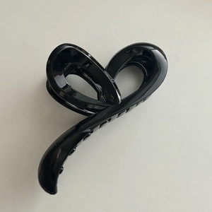 Détail de la grande pince à cheveux noire brillante avec un design torsadé et profilé