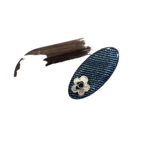 Denim blue oval hair clip with silver flower detail on dark blue textured fabric