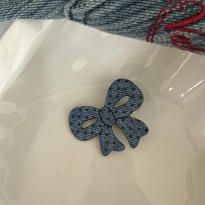 Dettaglio fiocco in denim blu con pois neri su piatto di ceramica bianca elegante