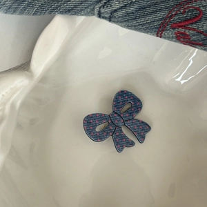 Dettaglio del fermaglio per capelli a fiocco in denim con pois rosa su vassoio in ceramica