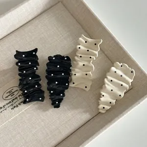 French wavy pleated hair clips with polka dots in black and cream on linen tray