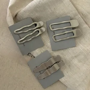 Vue détaillée de pinces à cheveux géométriques en métal argenté sur un tissu en lin