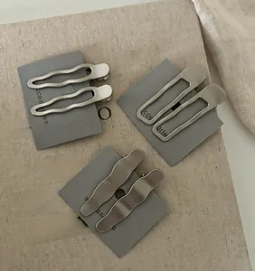 Détail de barrettes à cheveux géométriques en métal argenté mat sur support
