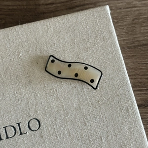 Close-up of wavy cream hair clip with black polka dots and a pearlescent acetate texture