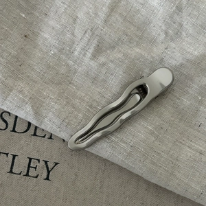 Barrette à cheveux ondulée en métal argenté brillant sur fond de lin texturé