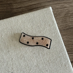 Detail of wavy acetate hair clip with pink marble texture and black polka dots