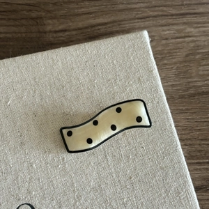 Macro shot of wavy acetate hair clip with classic cream background and black polka dots