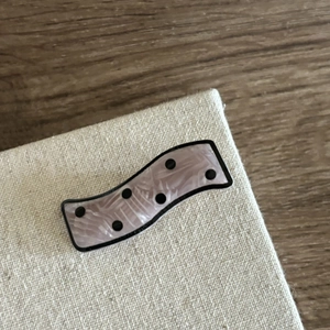Detailed view of wave-shaped pink marble acetate hair clip with stylish black polka dots