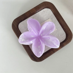 Elegant purple plumeria hair claw clip with marble texture on linen display