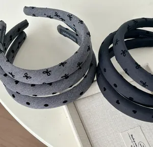 Detail of grey and navy bow-knot padded headbands with heart embroidery and handmade tag