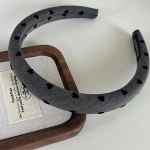 Handmade gray fabric headband with black flocked heart patterns and interior woven label