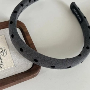 Close-up of grey padded headband with black polka dots and handmade interior label