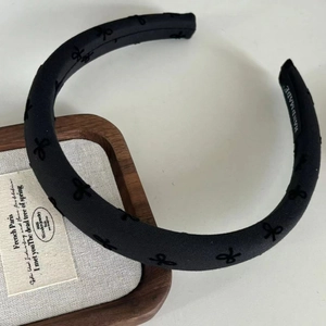 Close-up of black embroidered bow headband with visible handcrafted label on fabric