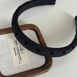 Detail of black fabric padded headband featuring laser-cut heart patterns and handmade label