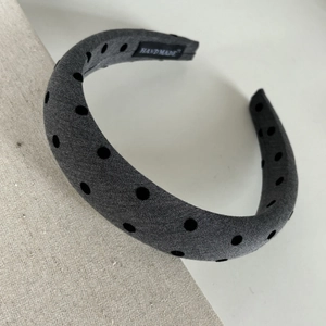 Macro detail of handmade grey polka dot sponge headband showing fabric texture and label