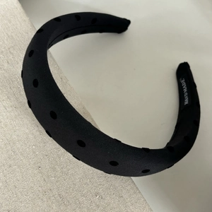 Detail of black polka dot headband showing the handmade label and premium fabric texture