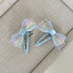 Dettaglio di fermagli blu glitterati con fiocchi in rete arcobaleno sul vassoio