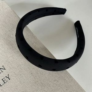 Detailed macro view of padded black headband featuring hollow heart textures and handmade label