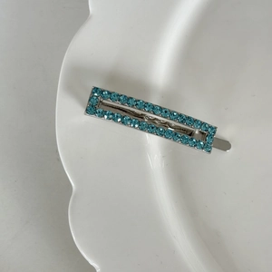 Detailaufnahme der rechteckigen silbernen Haarspange mit zwei Reihen blauen Strass